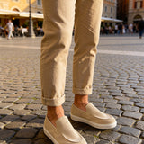 Beige suede loafers worn with cuffed pants, showing moc-style stitching