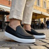 Black loafers with white soles, side profile on casual slip-on shoes
