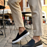 Black slip-on loafers with white soles, front step-in view