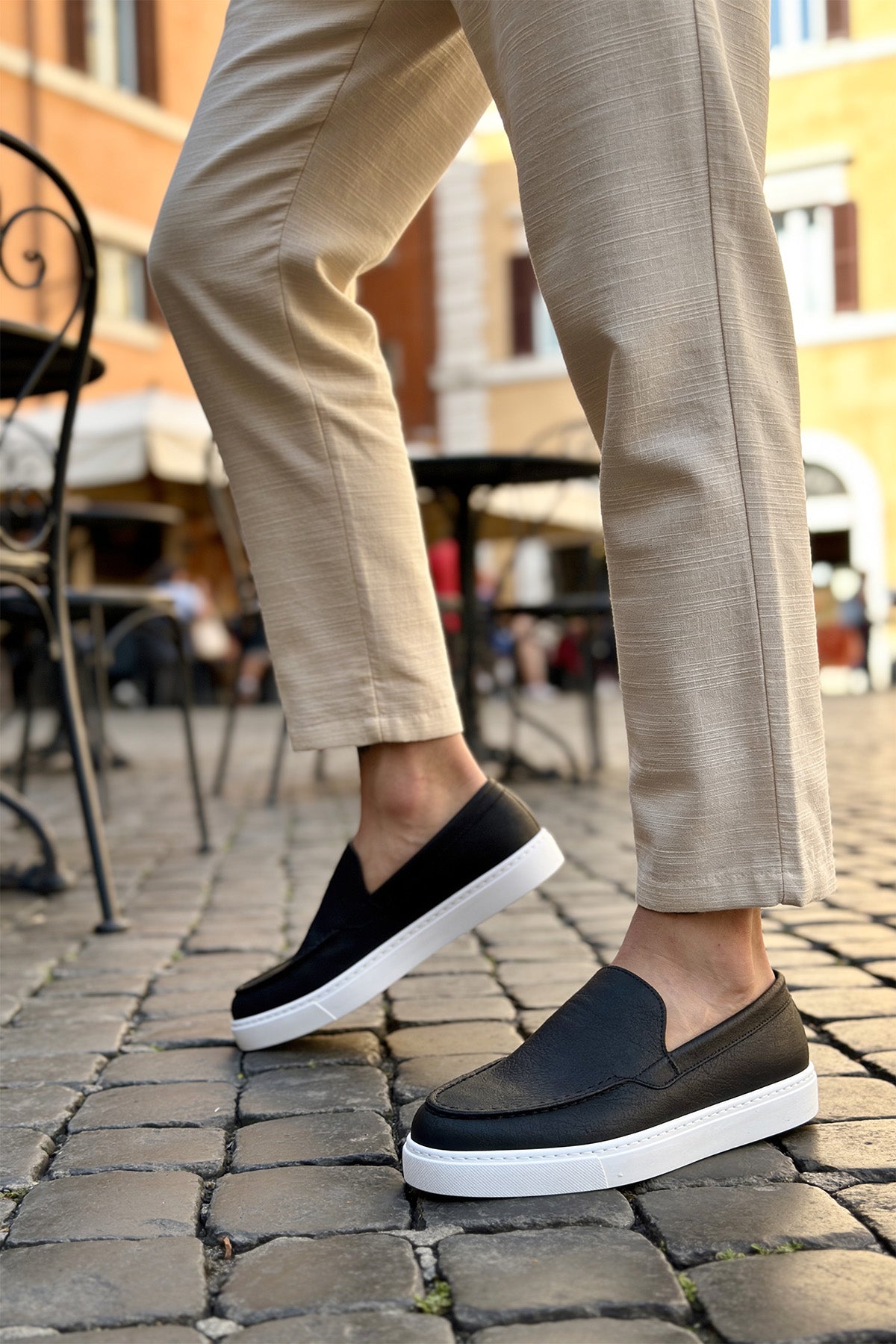 Black slip-on loafers with white soles, front step-in view