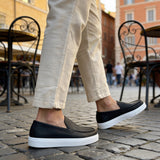 Black loafers with white rubber soles, three-quarter side view