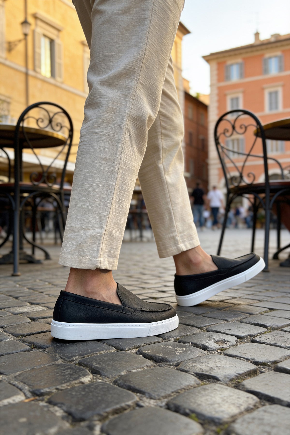 Black loafers with white rubber soles, three-quarter side view