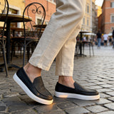 Black slip-on loafers with white soles, close side view pair