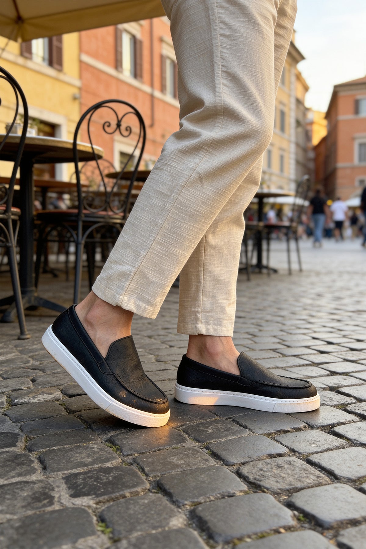 Black slip-on loafers with white soles, close side view pair
