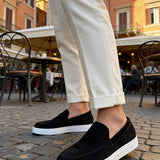 Black suede slip-on loafers with white rubber sole and stitched detail