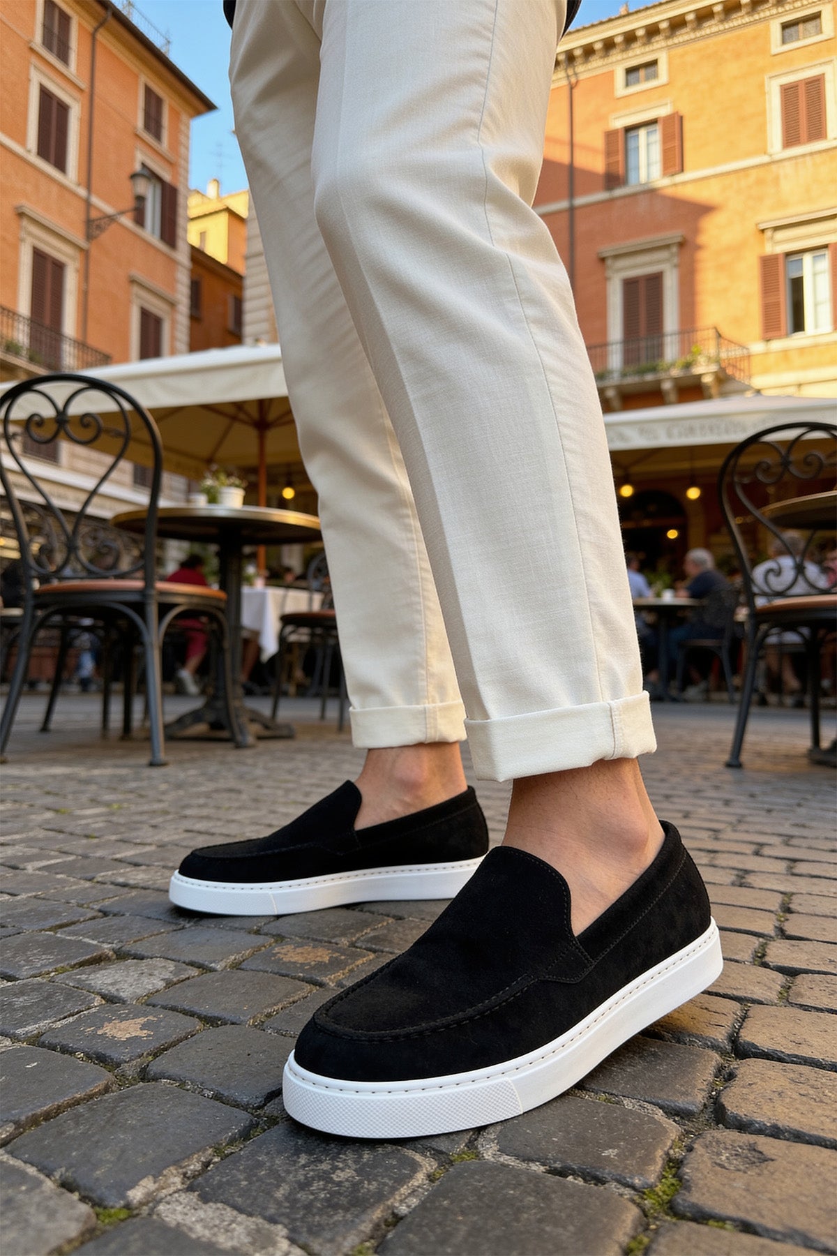 Black suede slip-on loafers with white rubber sole and stitched detail