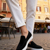 Black suede loafers with white sidewall trim, slip-on design
