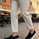 Black suede slip-on loafers with white sole and minimal stitched panels