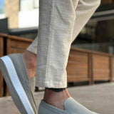 Men's gray suede slip-on loafers with low white rubber sole and moc toe stitching