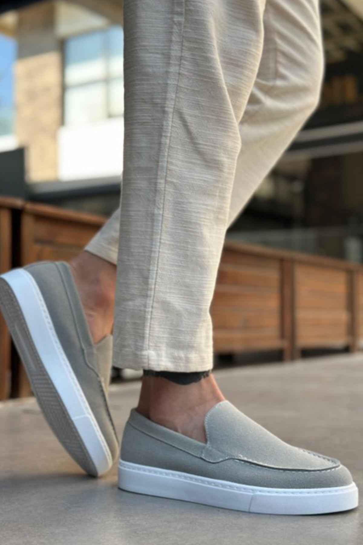 Men's gray suede slip-on loafers with low white rubber sole and moc toe stitching