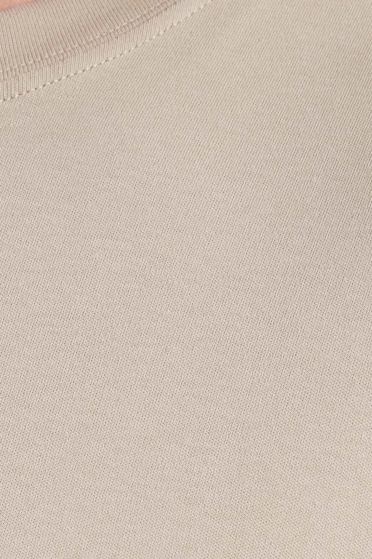 Beige T-shirt fabric texture with visible stitching