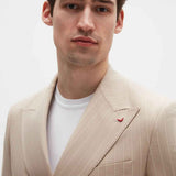 Beige striped men’s blazer with pocket square and gold-tone button details on lapel.