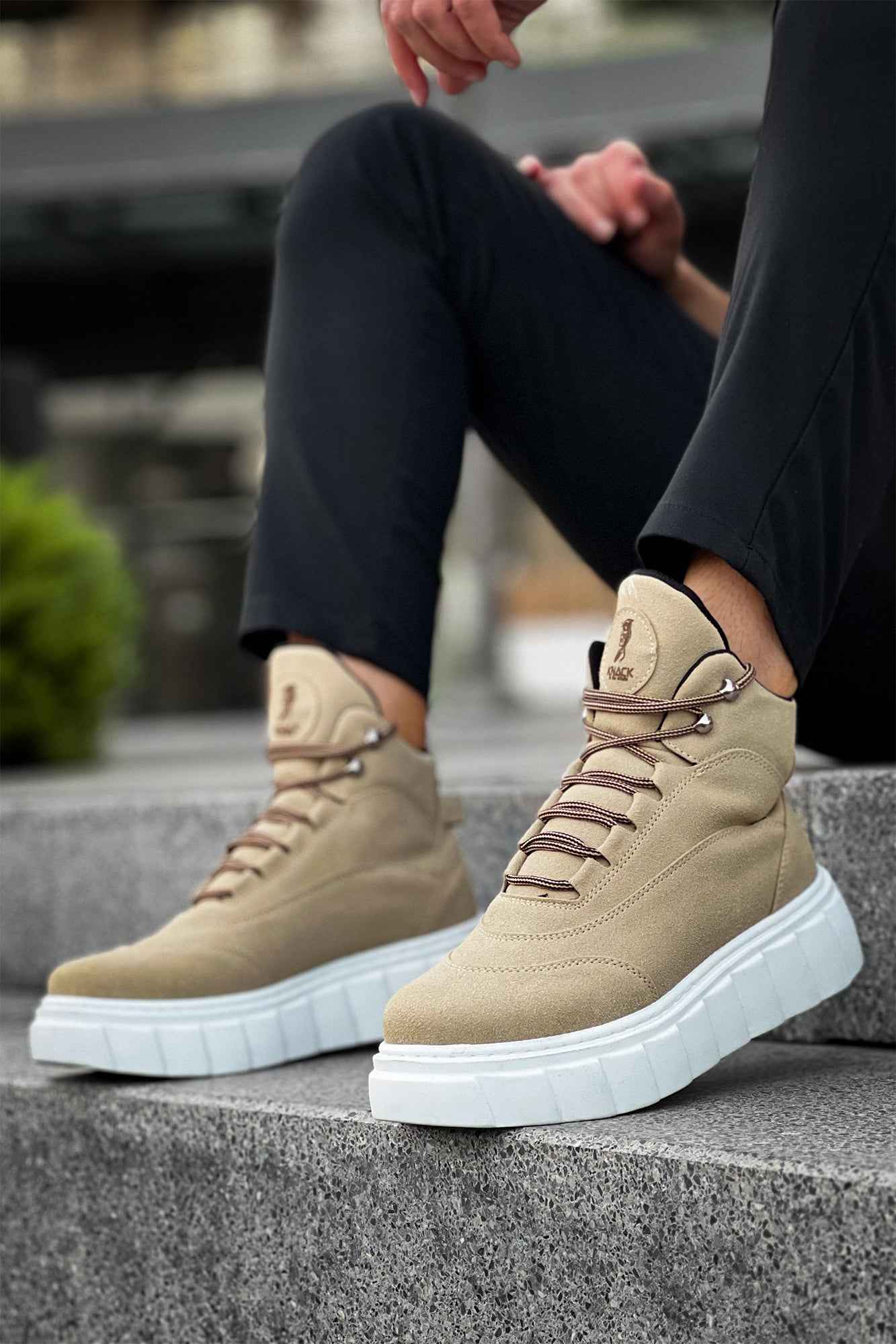 Beige suede lace-up boots with white platform sole, worn with dark pants
