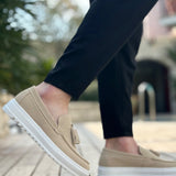 Beige suede loafers on foot, front side with tassel and white sole