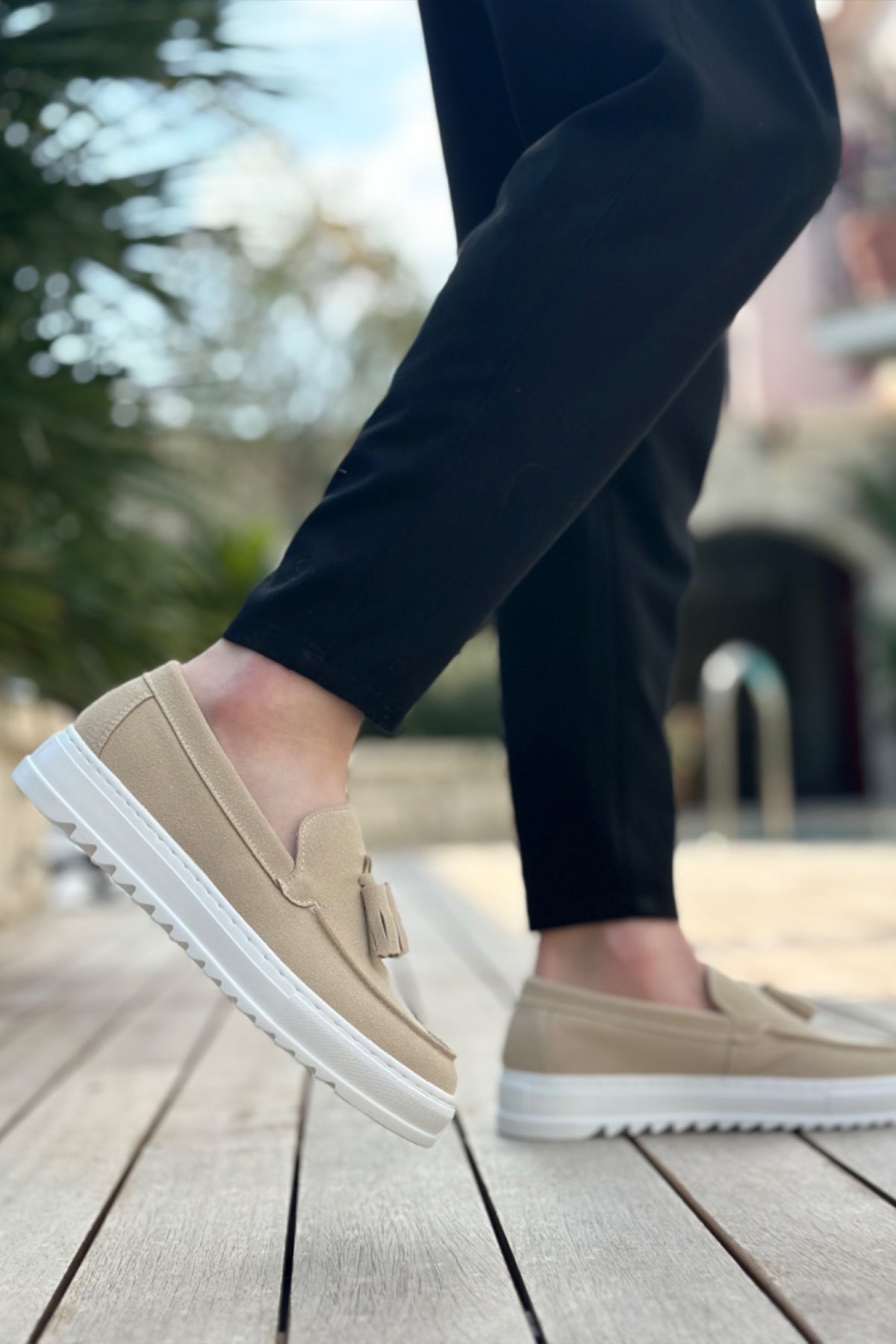 Beige suede loafers on foot, front side with tassel and white sole