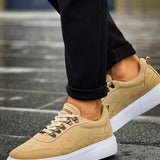 Beige suede low-top sneakers with white sole and lace eyelets, three-quarter view