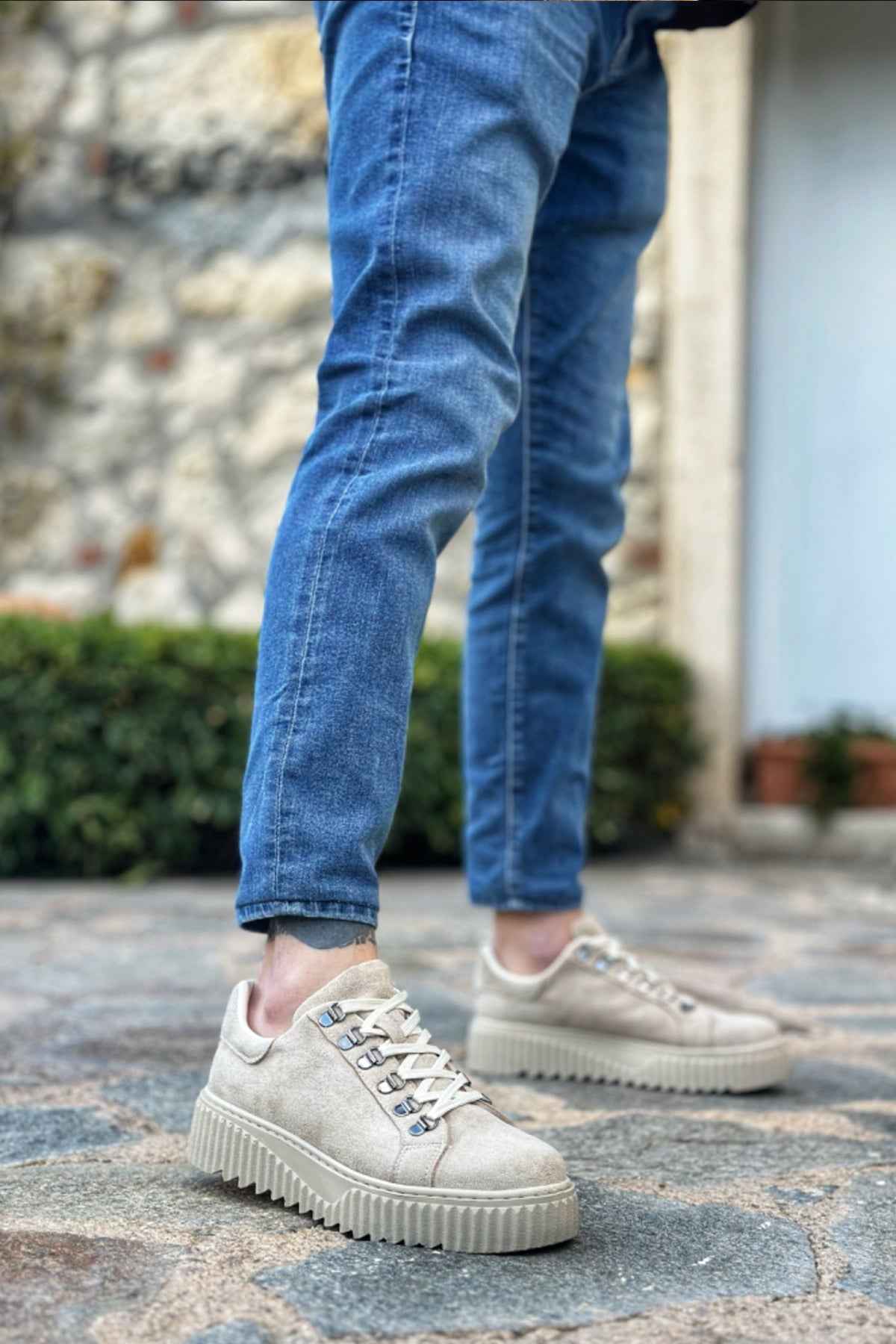 Beige suede low-top sneakers with lace-up closure and thick ridged rubber sole