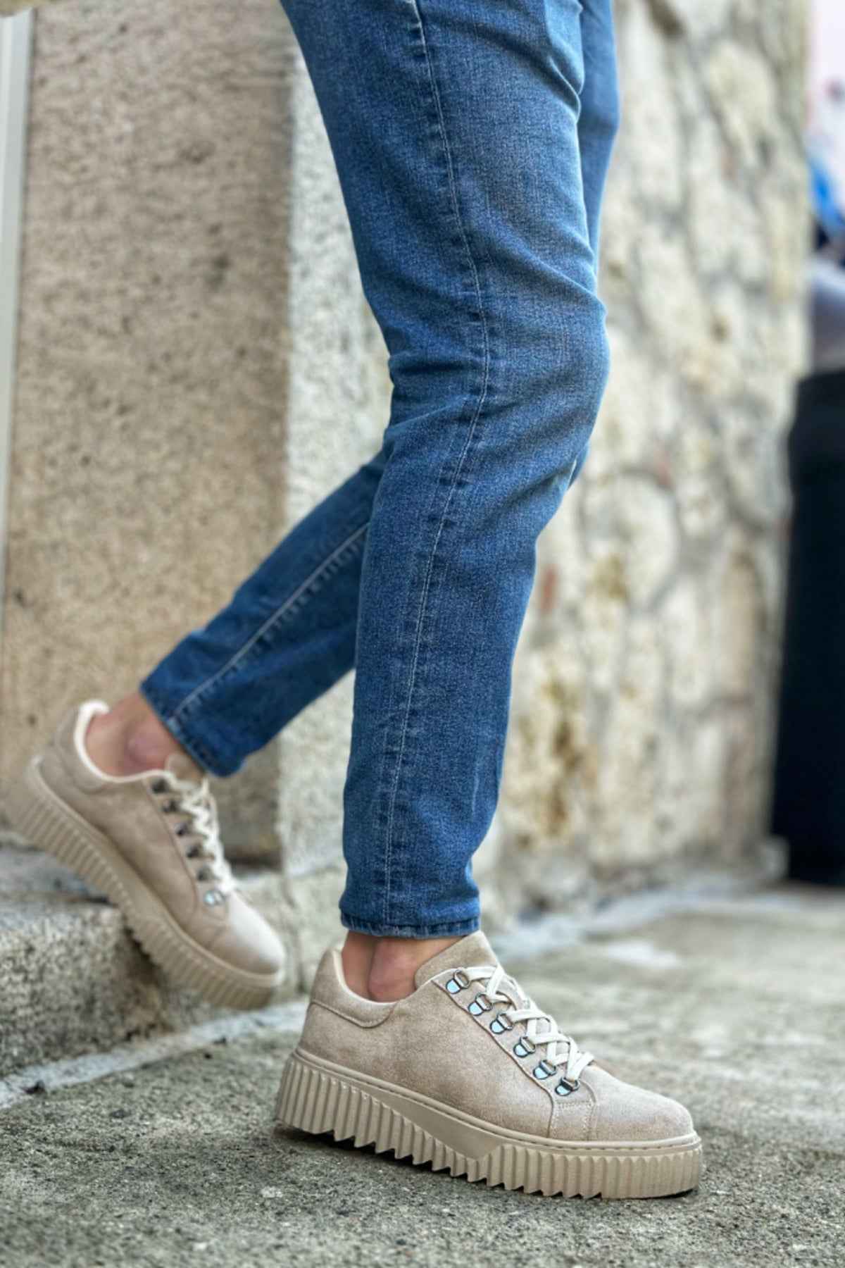 Beige suede sneakers with lace-up front and textured rubber sole, angled view