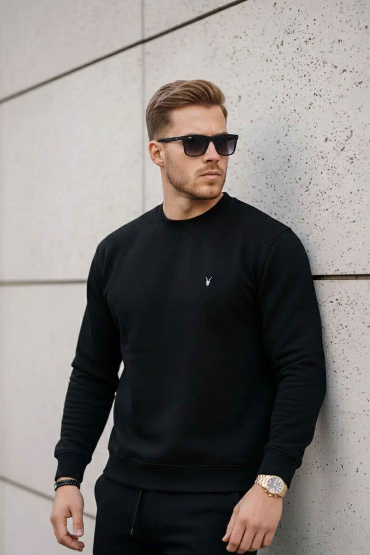 Black crewneck sweatshirt with long sleeves and small chest logo, ribbed hem