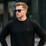 Black crewneck sweatshirt with ribbed cuffs and hem, small chest logo on chest