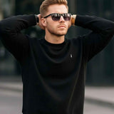 Black crewneck sweatshirt, ribbed cuffs and hem, small chest logo at center