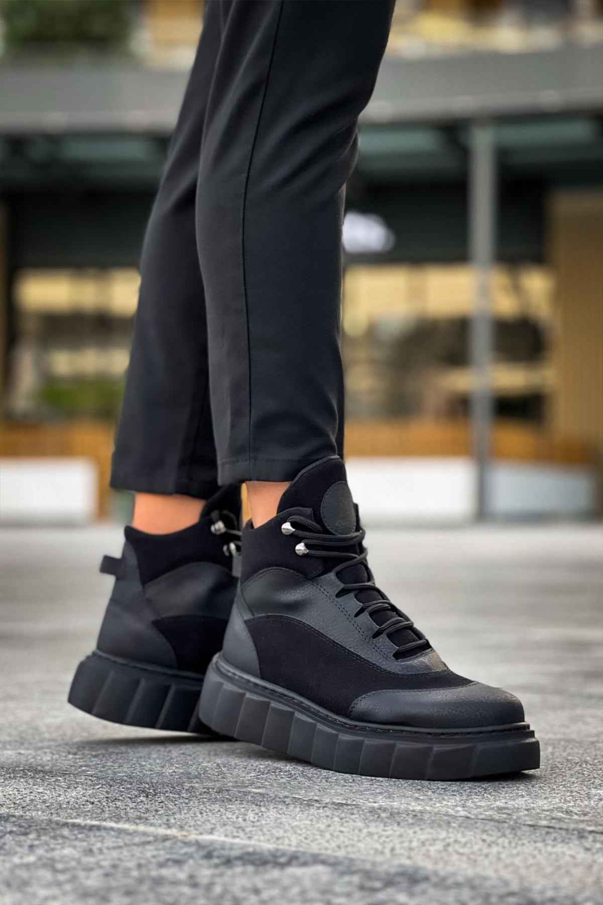 Black lace-up boots showing thick tread sole and black ankle pull tab