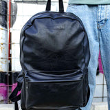 Black leather backpack held by top handle, front zip pocket
