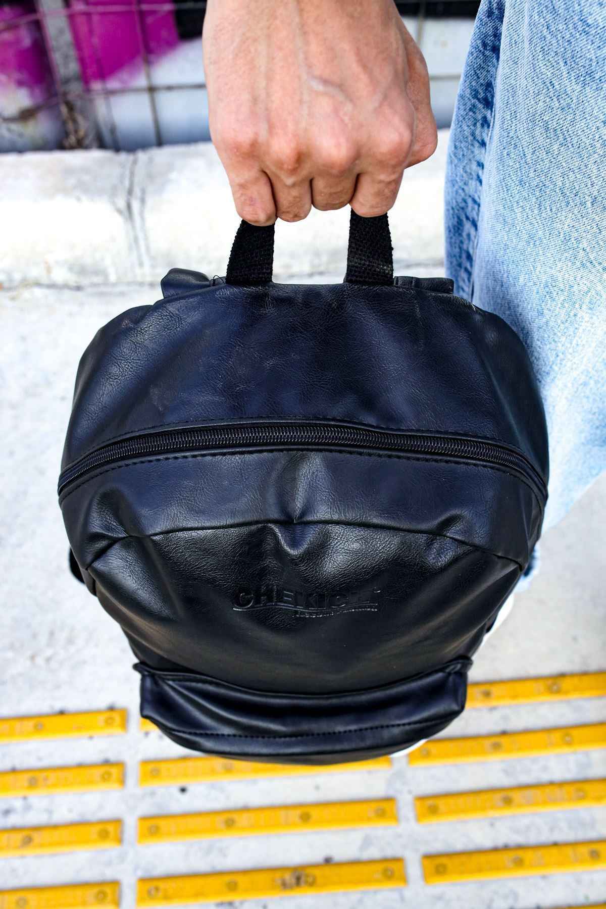 Black leather backpack with round top and front zip pocket