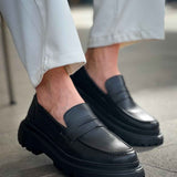 Black slip-on loafers, side view, smooth upper and tread sole