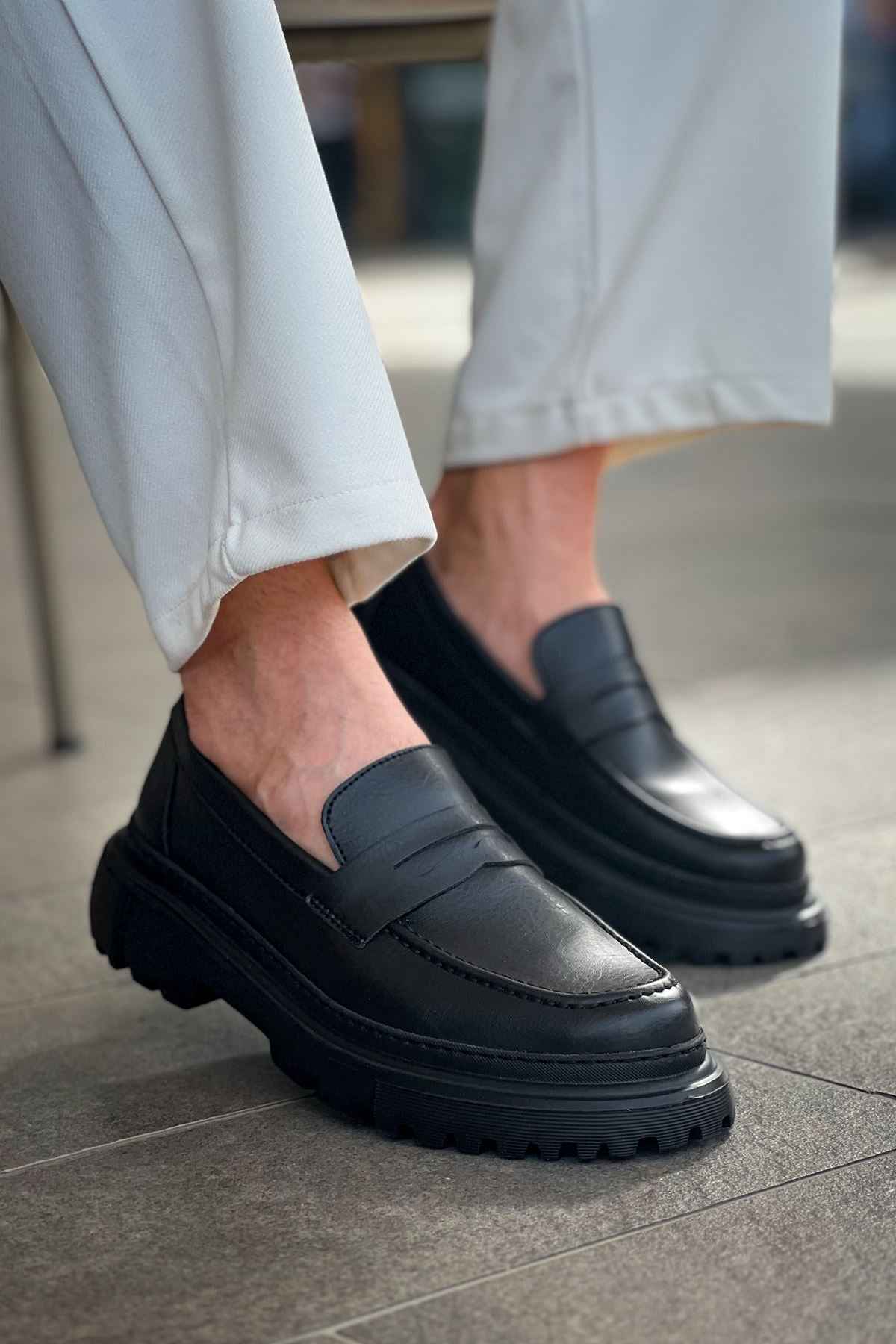 Black slip-on loafers, side view, smooth upper and tread sole