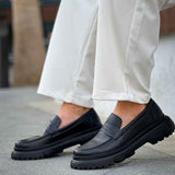Pair of black loafers on feet, side profile with platform sole