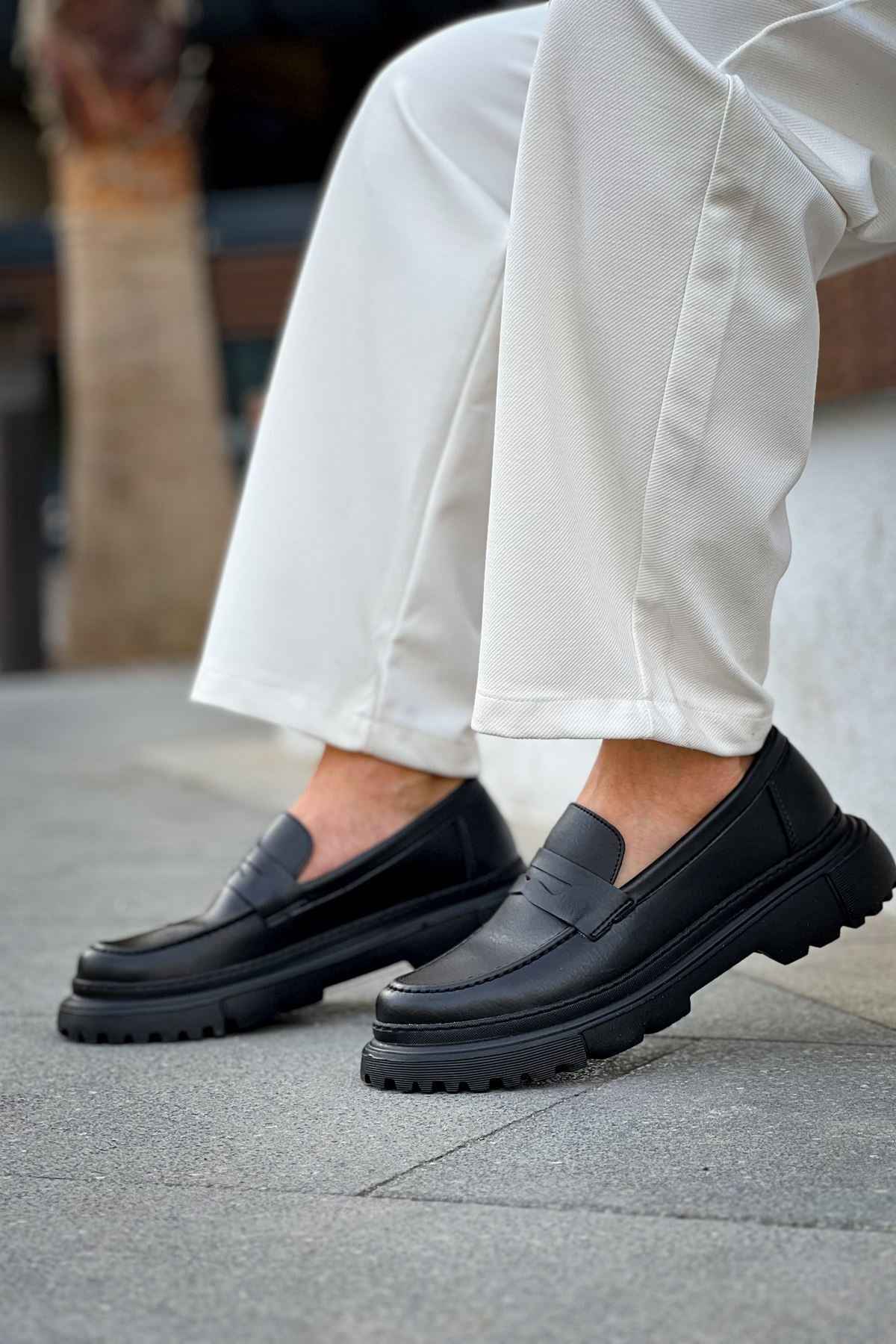 Pair of black loafers on feet, side profile with platform sole