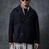 Men's oversized black double-breasted coat with wide lapels and flap pockets.