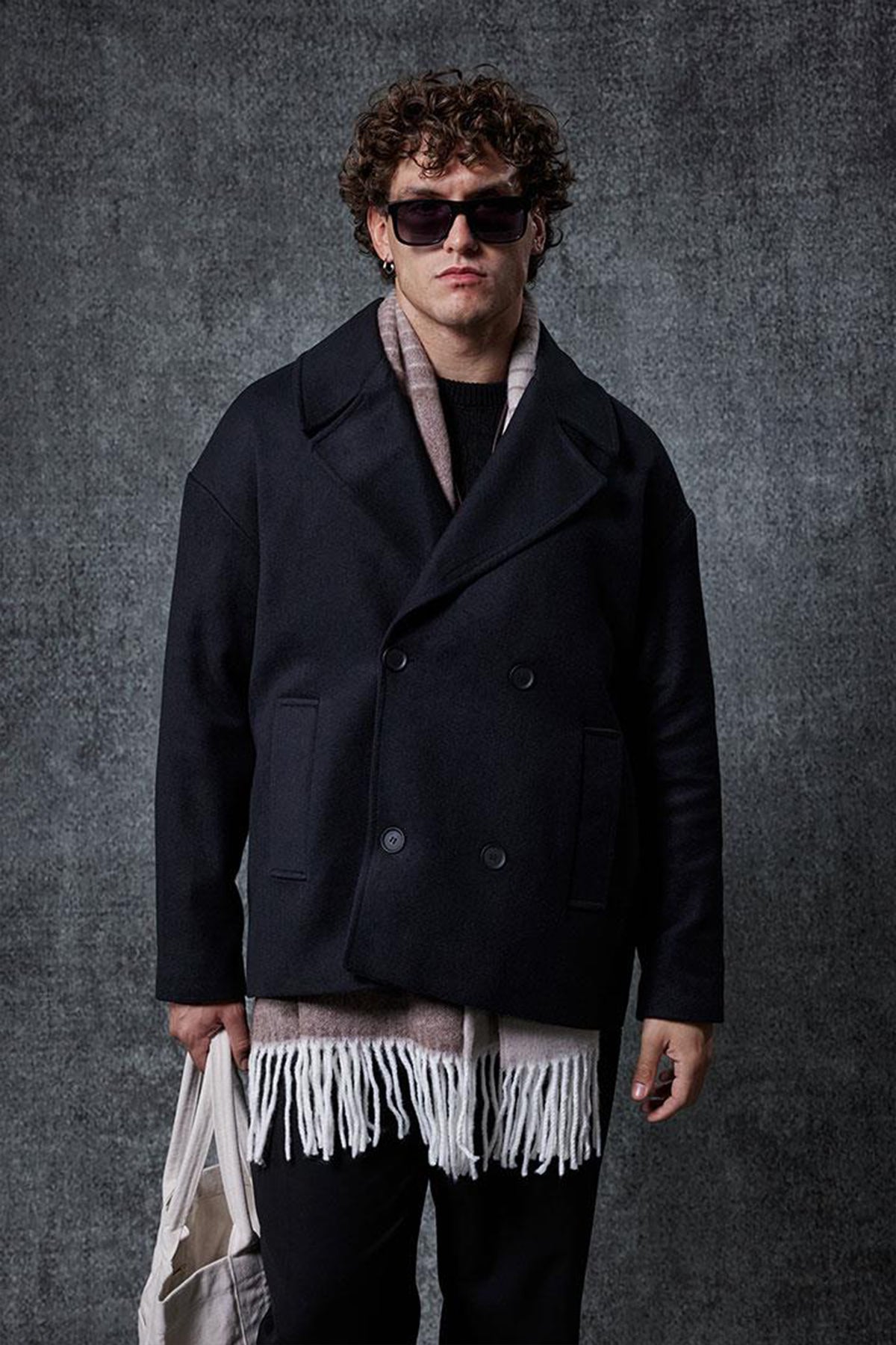 Men's oversized black double-breasted coat with wide lapels and flap pockets.