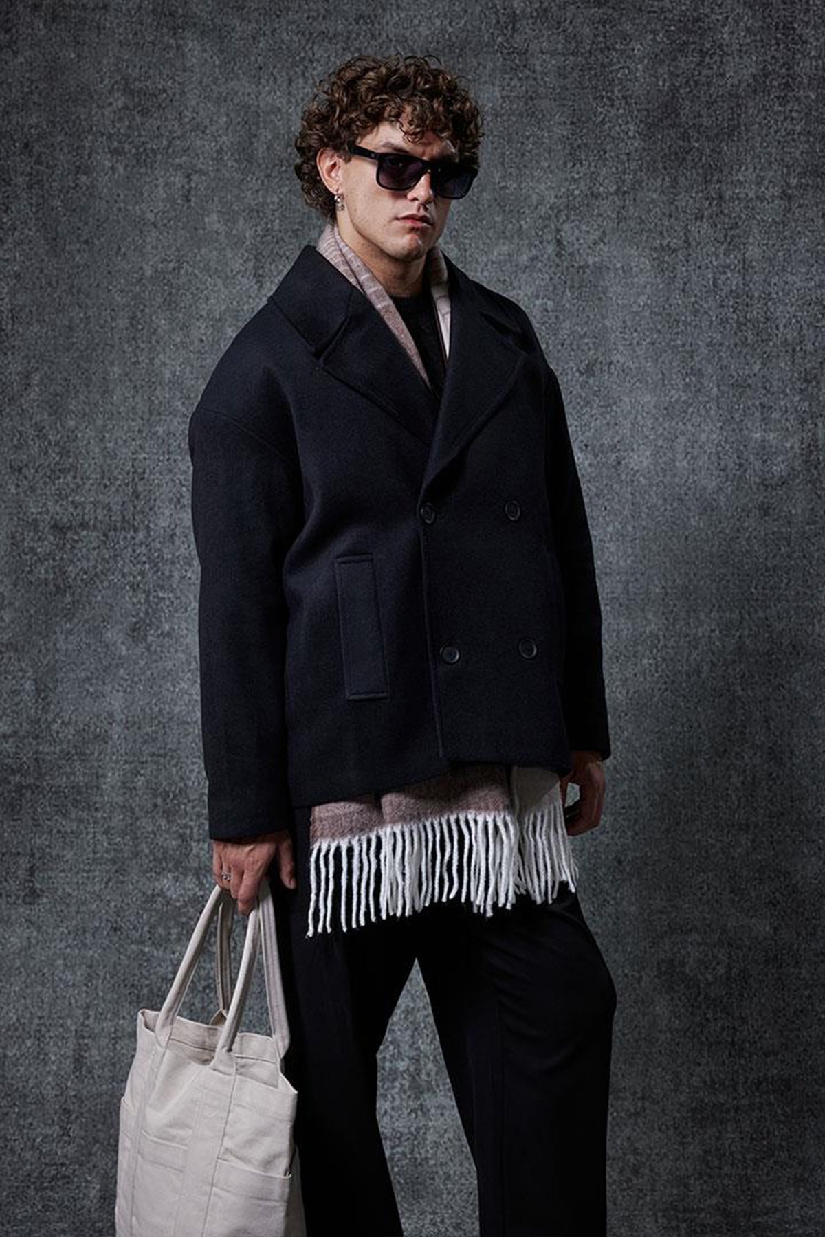 Men's oversized black double-breasted coat, 3/4 view, structured lapels and buttons.