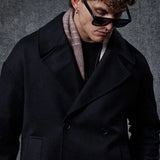 Men's oversized black double-breasted coat, close-up of wide lapels and buttons.