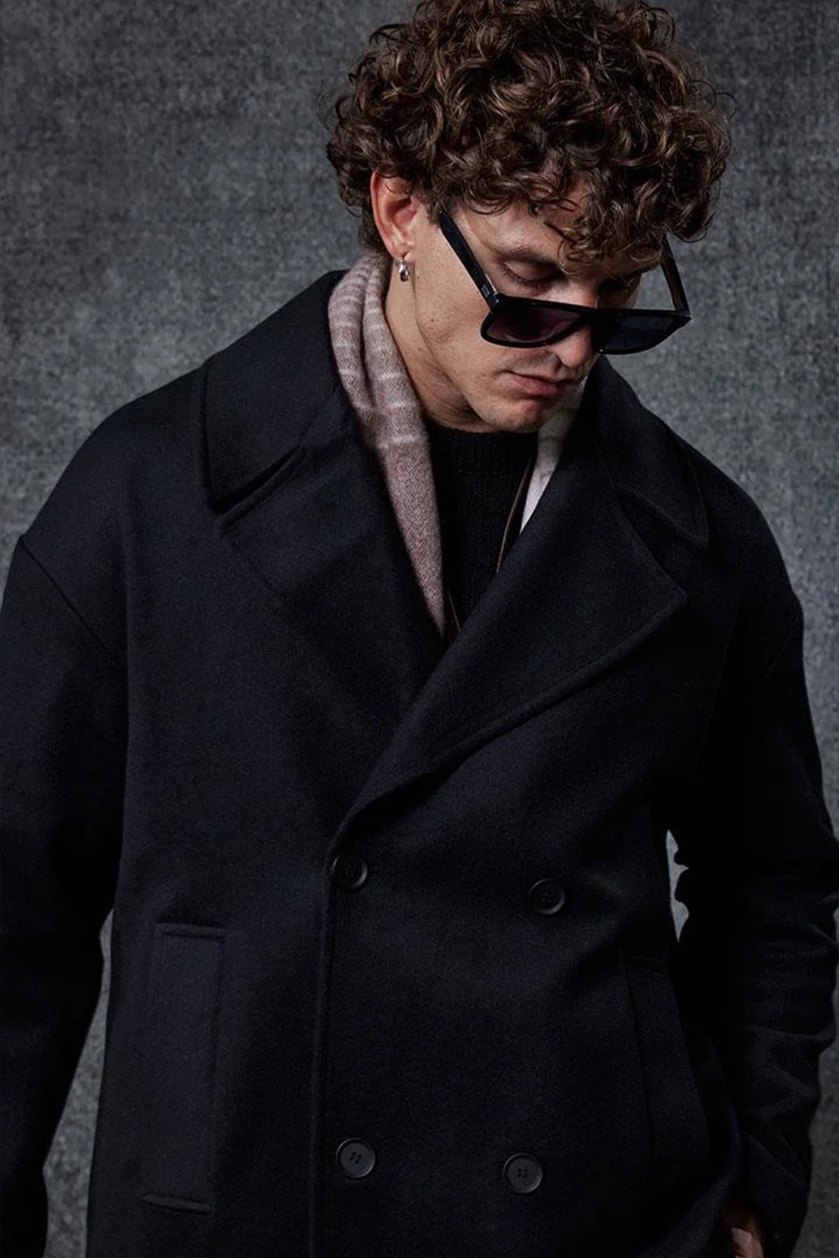 Men's oversized black double-breasted coat, close-up of wide lapels and buttons.