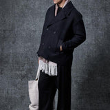 Men's oversized black double-breasted coat with flap pockets and fringed hem detail.