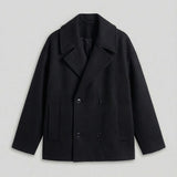 Black oversized double-breasted coat on white background, front view with button closure.