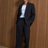 Black oversized suit with jacket and trousers, front view on male model
