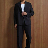 Black oversized suit jacket and trousers, hands clasped front view