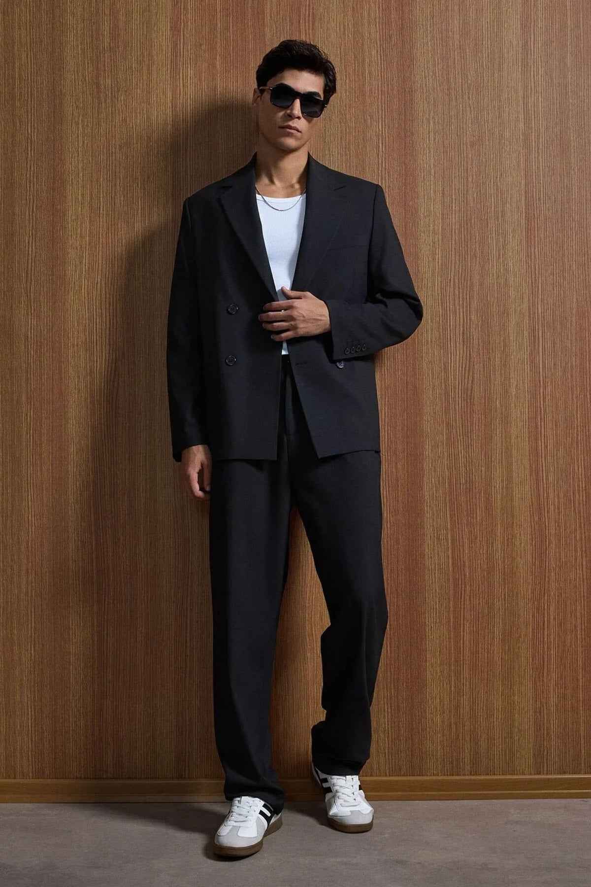Black oversized suit jacket and trousers, hands clasped front view