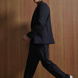 Black oversized suit jacket and trousers, side profile walking stance