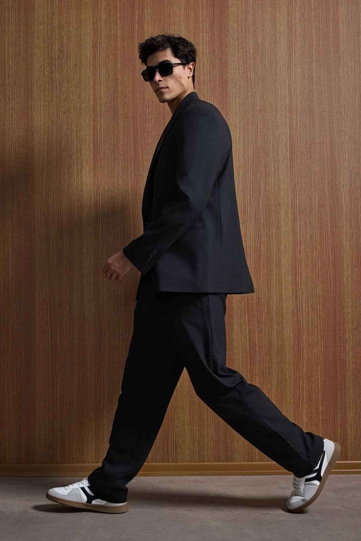 Black oversized suit jacket and trousers, side profile walking stance