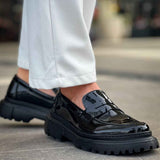 Black patent leather loafer with chunky tread sole and strap detail, side view
