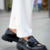 Black patent leather loafer with chunky tread sole, front angle, slip-on design