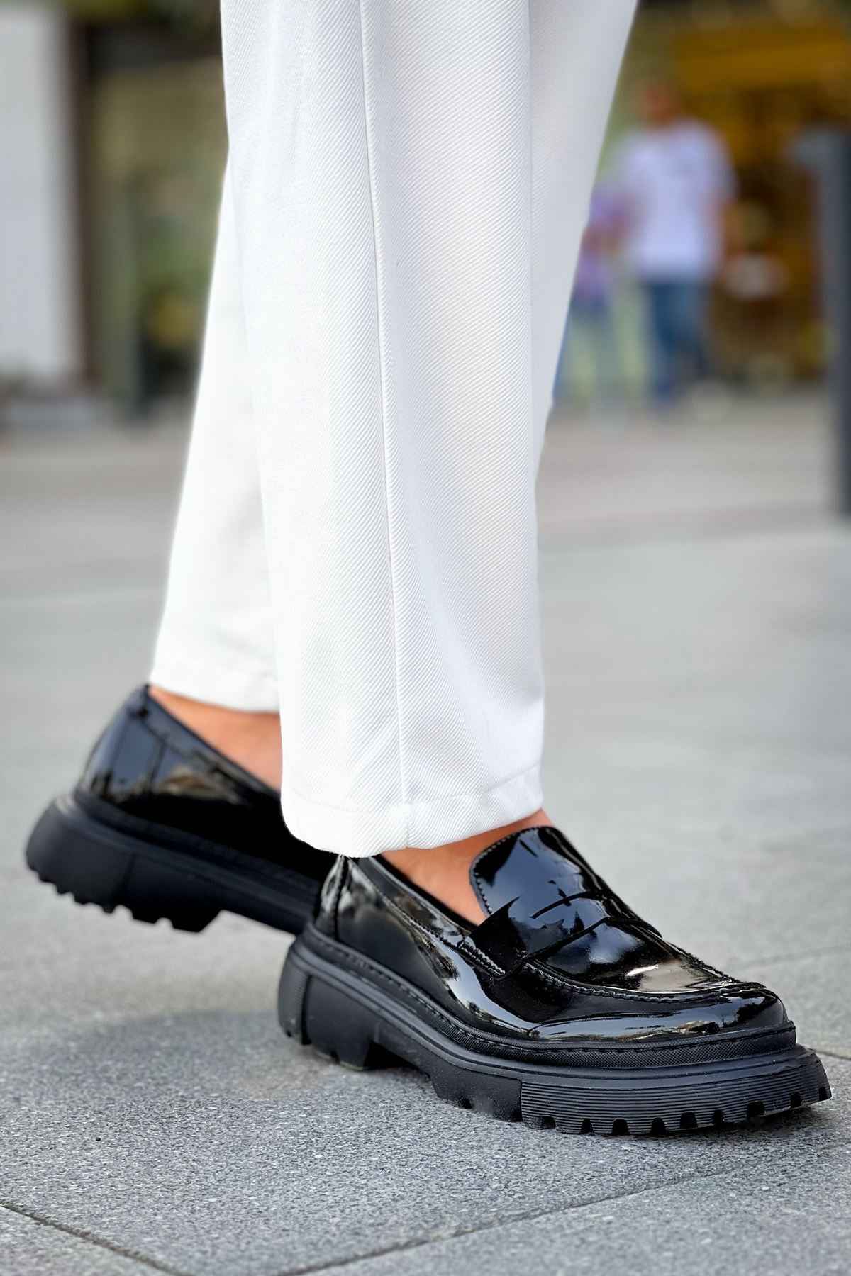 Black patent leather loafer with chunky tread sole, front angle, slip-on design