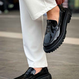 Black patent leather loafer with strap detail and thick tread sole, side view