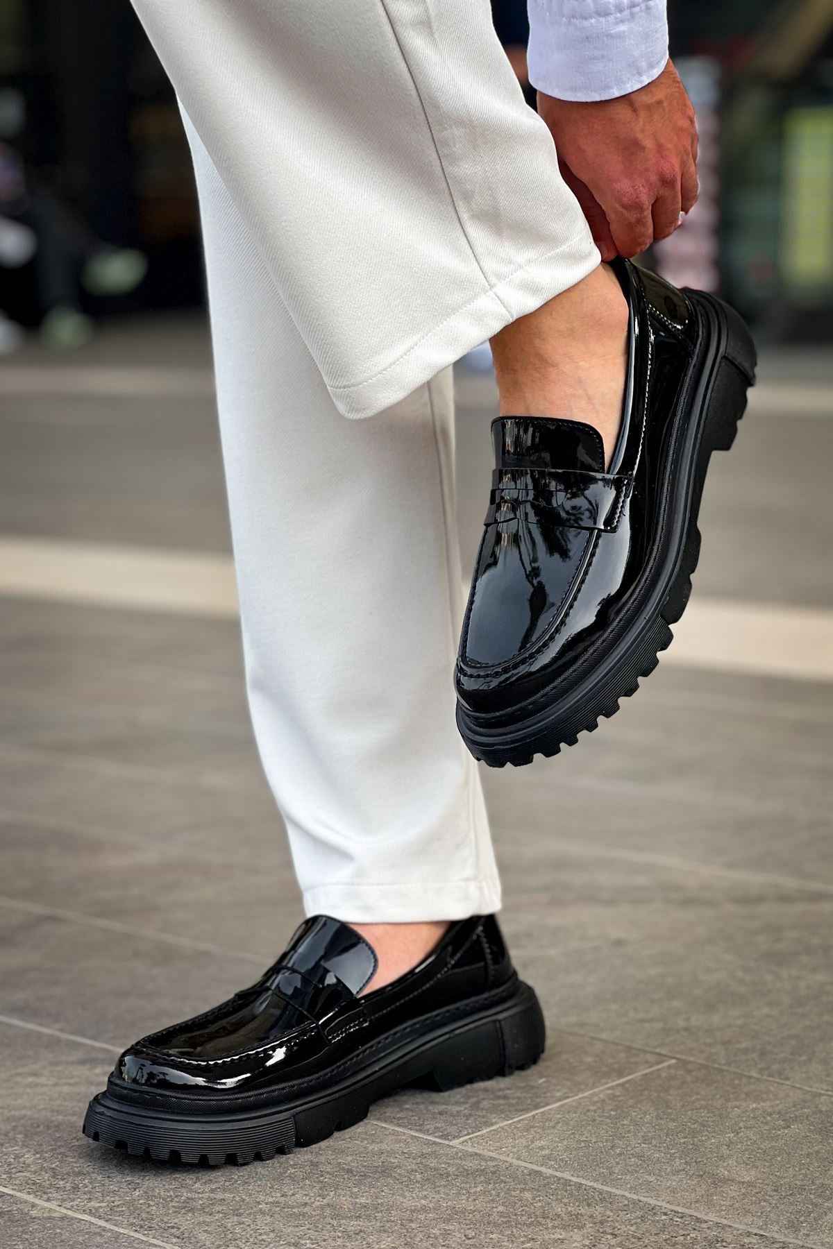 Black patent leather loafer with strap detail and thick tread sole, side view