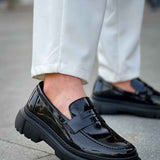 Black patent leather loafer with chunky sole and strap detailing, close side view